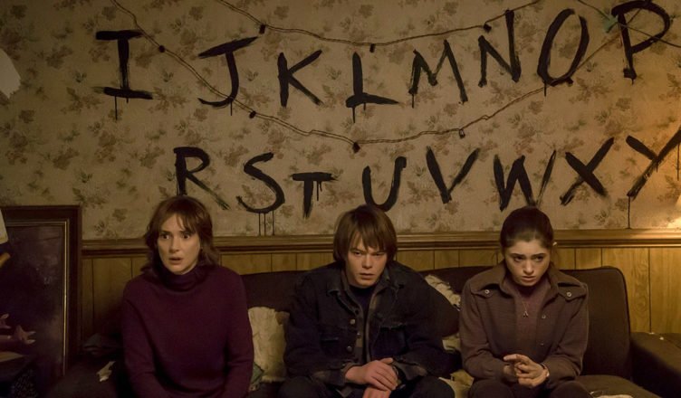 Stranger Things Joyce (Winona Ryders) Jonathan (Charlie Heaton) und Nancy (Natalia Dyers) sitzen auf einem Sofa