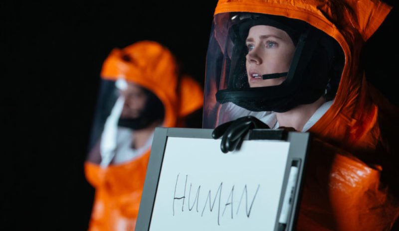 Amy Adams als Louise hält ein Schild mit dem Wort "Human" in "Arrival" (2016)