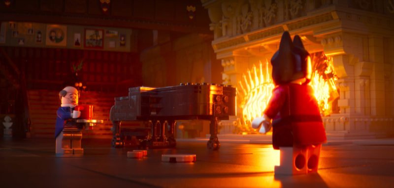 Bruce Wayne und Butler Alfred unterhalten sich in einem Saal mit brennendem Kamin in The Lego Batman Movie