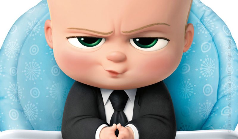 Das Boss Baby schaut mit gefalteten Händen und Business-Anzug verschmitzt und kritisch