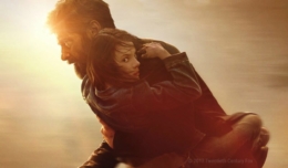 Logan hält ein Mädchen beschützend auf dem Arm und rennt