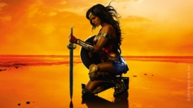 Gal Gadot kniet in voller Rüstung als Wonder Woman am Strand