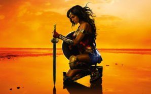 Gal Gadot kniet in voller Rüstung als Wonder Woman am Strand