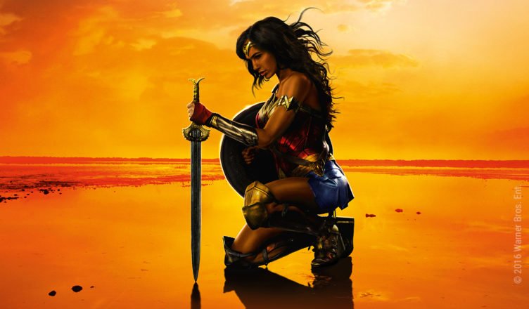 Gal Gadot kniet in voller Rüstung als Wonder Woman am Strand