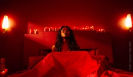 Bilquis der Göttin der Liebe sitzt in einem Bett in einem roterleuchteten Raum in American Gods Staffel 1