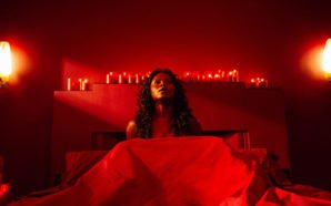 Bilquis der Göttin der Liebe sitzt in einem Bett in einem roterleuchteten Raum in American Gods Staffel 1