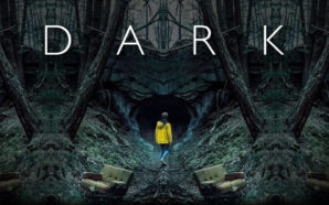 Jonas Kahnwald steht in einer gelben Regenjacke vor einer Höhle in Winden in Dark – Staffel 1
