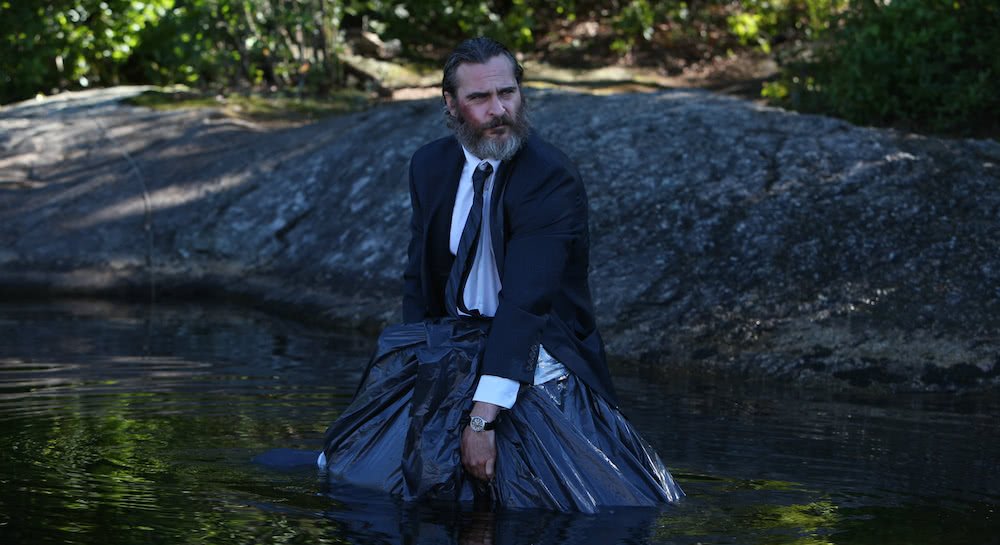 Joaquin Phoenix lässt einen Leichensack im See verschwinden in einem Szenenbild für Kritik A Beautiful Day