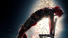 Titelbild Kritik Deadpool 2 mit Ryan Reynolds als Deadpool, der sich von einem Schauer von Patronen berieseln lässt
