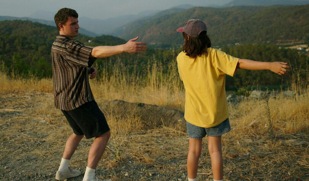 Links der junge Vater Mescal im gestreiften Hemd, rechts die Tochter Sophie im gelben T-Shirt. Sie machen Tai Chi-Bewegungen.