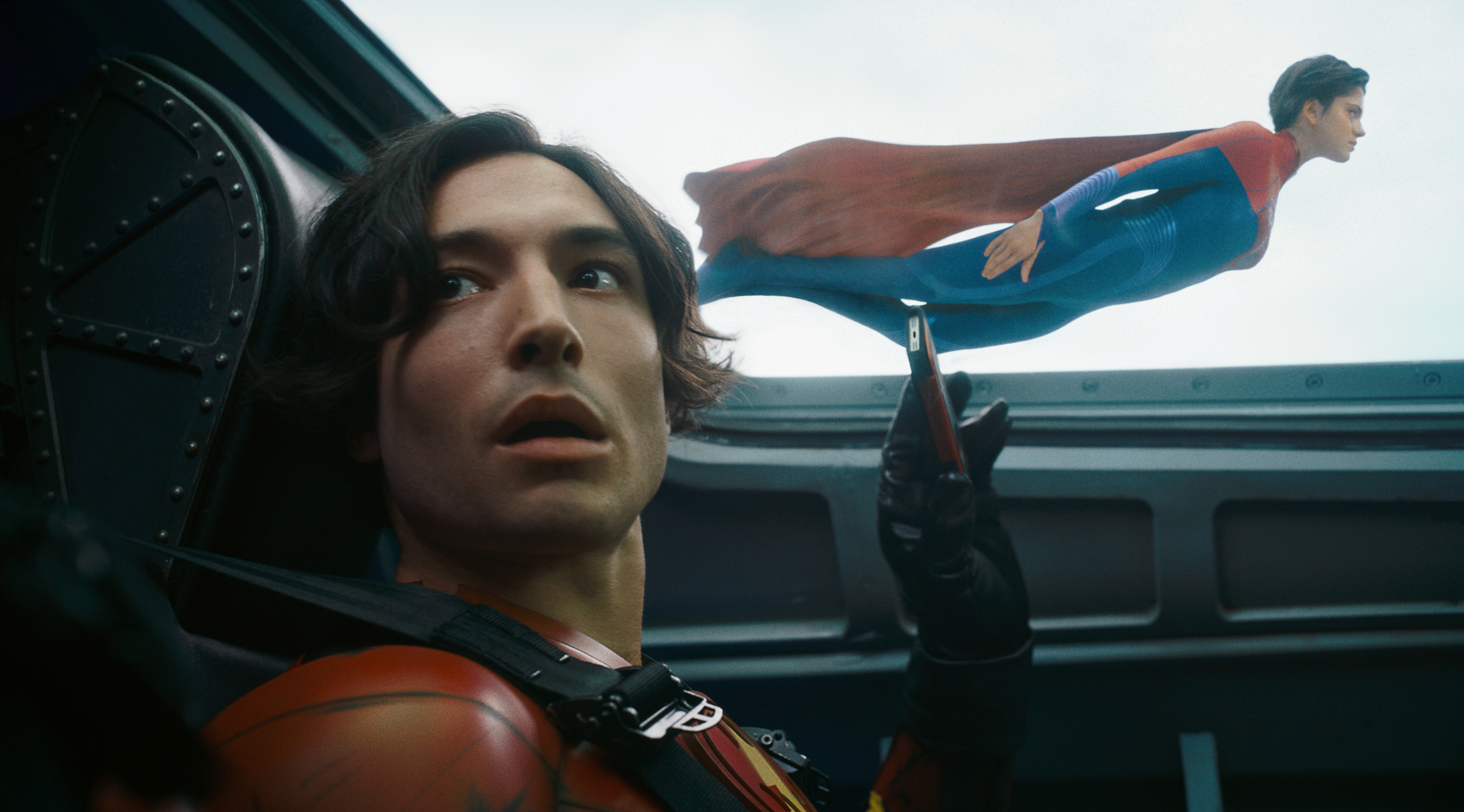 Supergirl (Sasha Calle) fliegt neben dem Flugzeugsitz von Barry Allen (Ezra Miller)